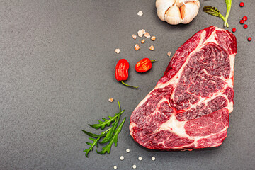 Raw Ribeye steak with spices and herbs. Dry aged meat, traditional food for grill. Black background