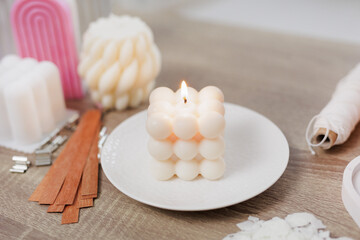 Fototapeta na wymiar Burning beautiful white bauble candle on stand