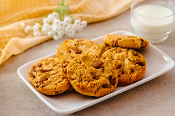 Chocolate chip cookies on white plate and glass of milk
