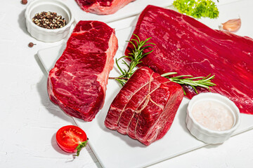 Set of various steaks with spices and herbs. Ribeye, eye round, flank and striploin steaks