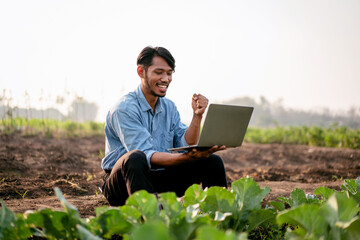 Smart farmer raising arm to celebrate after using laptop to exam