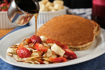 Closeup shot of a sweet dessert with pancakes, strawberries, bananas and nuts