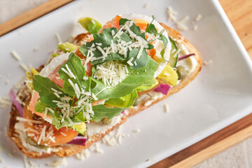 Closeup shot of bruschetta with poached eggs, avocado, tomato and onions arugula