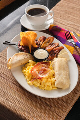 Vertical closeup shot of a typical breakfast with fried plantains, tortilla, eggs and bacon