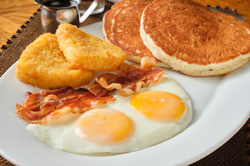 Closeup shot of an American breakfast with pancakes, eggs, hash brown and bacon