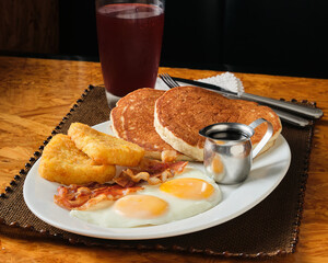 Closeup shot of an American breakfast with pancakes, eggs, bacon, and hash brown