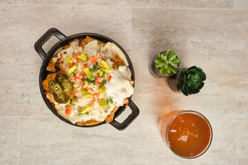 Top view of Mexican nachos with topping served in a pan