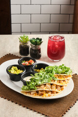 Vertical closeup shot of quesadillas served with a drink and sauces
