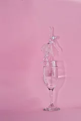 Photo sur Plexiglas Monument historique Vertical shot of a crystal ballerina standing on a glass of water isolated on a pink background