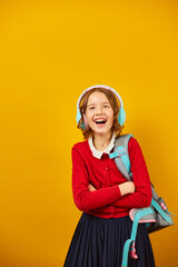 Happy schoolgirl with backpack, headphone having fun