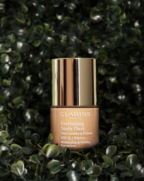 Vertical shot of "Clarins" Everlasting Youth Fluid Foundation jar against natural background
