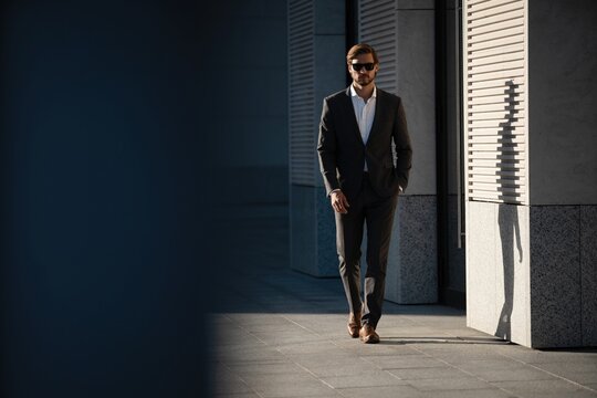 Elegant handsome man in classic suit standing near the office building.