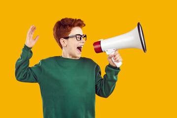 Funny red-haired handsome boy with glasses, dressed in green sweater, shouts with his mouth wide...