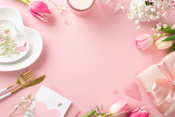 Fototapeta na wymiar Stylish Mother's day celebration table. Top view flat lay of plates, cutlery, tulips, postcard, gift box, and decorative hearts on pastel pink background with a space for promotional content or text