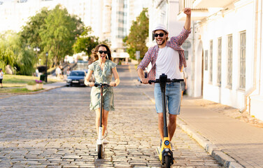 Happy young couple in love on vacation having fun, driving electric scooter through the city. Eco transport © opolja