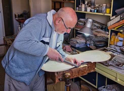 Master artisan luthier working on the creation of a cello.
