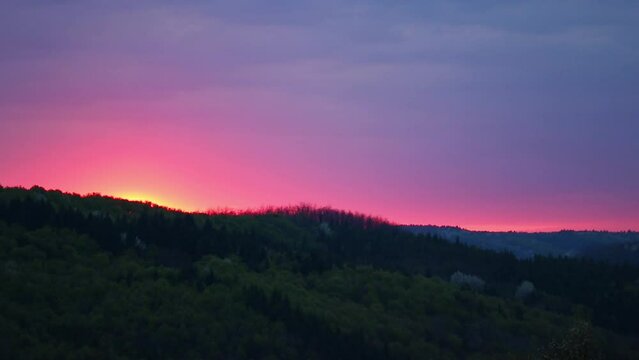 Scenic view of the pink sunset above the forest and mountains