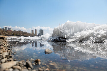 Obraz premium Ice drift on the river. Melting ice floes against the backdrop of the city's waterfront. Ice drifts.