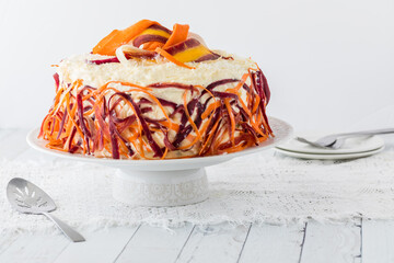 A colourful carrot cake garnished with rainbow carrot shavings.