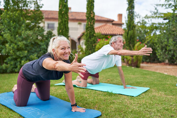 Happy senior couple practicing yoga in villa garden grass