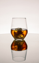 Iced Alcohol drink in a glass cup with reflection on a mirror surface