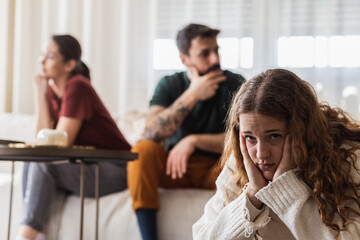Parents in a disagreement after a parents meeting in school, daughter feeling sad.