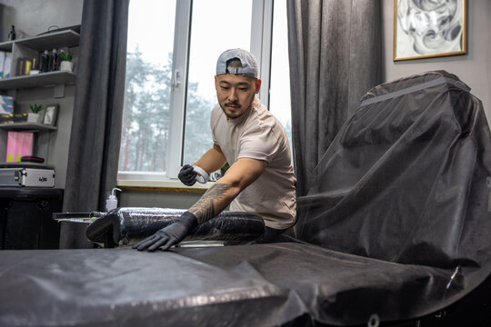 Asian tattoo master preparing couch for tattoo session