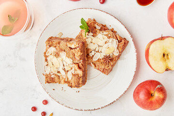 Slices of traditional apple pie with almond flakes and apples. Cranberry natural tea flat lay