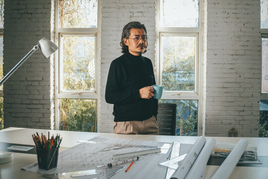 Middle-aged and elderly designer holding a cup in the studio