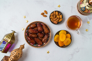 Eid al-Fitr holiday concept with sweet dried dates, fruits and decorations on bright background. Top view from above