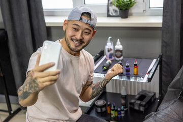 Young asian tattoo salon owner feeling good at his workplace