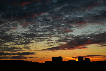 Suburban sunset over the houses. The sky is orange with blue clouds.