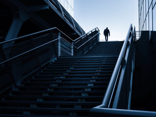 Une montée d'escalier dans un quartier d'affaire avec une silhouette d'homme