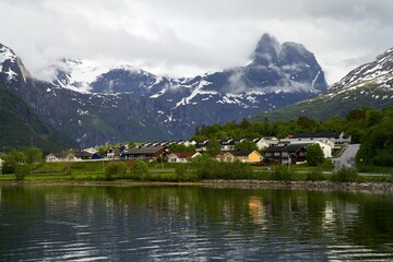 Wooden residential houses near snow-covered mountain peaks and a lake, Fjord coast, Norway