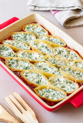 Baked pasta stuffed with cheese and spinach in tomato sauce. Vegetarian food. Italian food.