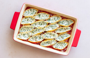 Baked pasta stuffed with cheese and spinach in tomato sauce. Vegetarian food. Italian food.