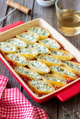 Baked pasta stuffed with cheese and spinach in tomato sauce. Vegetarian food. Italian food.