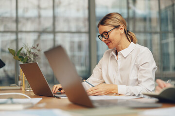 Middle age woman office worker working on laptop while sitting in modern coworking