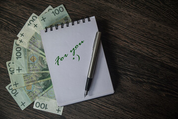 banknoty ułożone pod notesem z napisem FOR YOU na blacie.