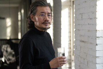 Middle-aged and elderly designer holding a cup in the studio