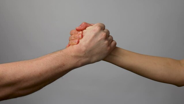 Two hands handshake on gray background.