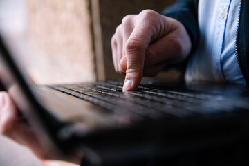 Men's hands typing on a laptop keyboard. Selective focus