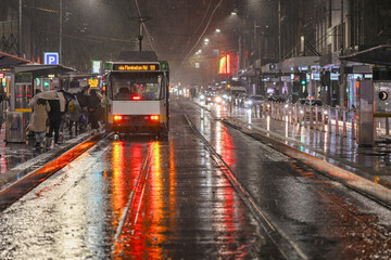 People board a tram on a wet rainy night in Melbourne, Australia