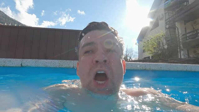 a man dives in the pool and takes a picture of himself.
