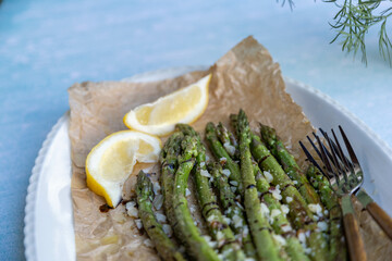 Cooked green asparagus with parmesan lemon and balsamic. On a white tray and a blue...