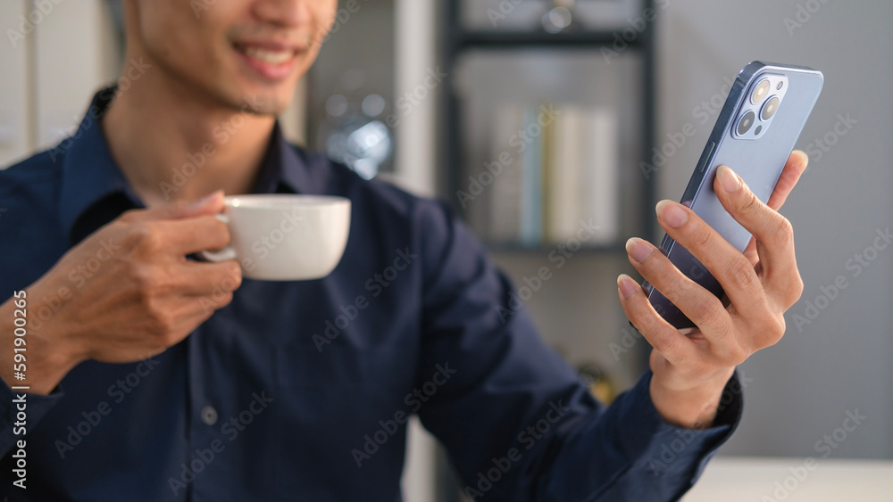 Poster smiling businessman drinking coffee and chatting or typing text message on smartphone.