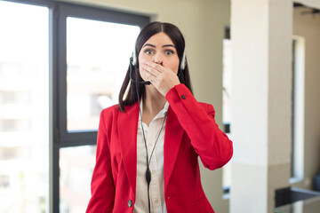 pretty young woman covering mouth with a hand and shocked or surprised expression. telemarketer concept