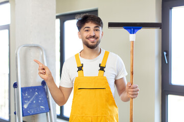 young handsome man smiling cheerfully, feeling happy and pointing to the side. windows washer...