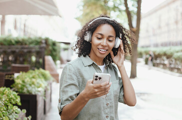 Young beautiful woman in headphones enjoying life outdoor, Happy african american student girl...