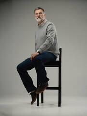 Portrait of a casual senior sitting on a chair on white background